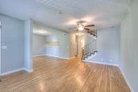 Bright and inviting open floor plan featuring elegant flooring, modern neutral walls, and ample natural lighting. The airy layout seamlessly connects living, dining, and kitchen areas, ideal for entertaining or cozy gatherings.