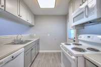 Clean, bright kitchen featuring contemporary cabinetry, pristine white appliances, and sleek countertops. The practical layout makes cooking enjoyable, while stylish finishes add sophistication and functionality.