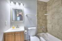 Beautifully updated private full bathroom showcasing stylish countertops, ample cabinetry, modern fixtures, and a tiled shower-tub combination. The spacious vanity area provides a luxurious feel and plenty of room for daily routines.