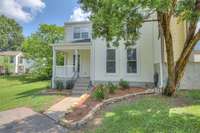 A closer view of the entrance highlights the home's welcoming charm, showcasing a lovely garden bed bordered by attractive stonework. The quaint porch offers a cozy and serene space to enjoy the neighborhood views.