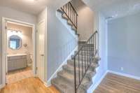 Welcoming staircase area with soft, plush carpeting leading to the upper level. Adjacent bathroom and closet showcase convenience and thoughtful design, with easy access from the main living spaces, enhancing comfort and functionality.