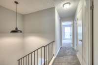 The upper-level hallway boasts soft carpeting, modern lighting, and easy access to bedrooms and bathrooms, offering comfort and convenience in a thoughtfully designed layout.