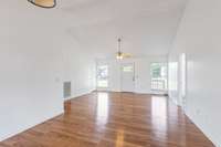 Large Living Room with vaulted ceilings, fresh paint, gleaming LVP floors, and open-concept floorplan.