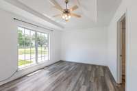 Primary Bedroom includes trey ceilings, LVP flooring, Bathroom Suite with walk-in closet, lots of natural light. It is situated on the other side of the home than the two secondary bedrooms.