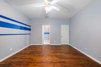 The primary bedroom with its pretty floors and custom paint has a walk-in closet, ceiling fan and private bath.
