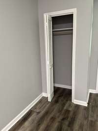 This is the coat closet in the living room, and a more accurate color of the flooring. The walls are freshly painted a light gray, offset by the rich brownish-gray floor color. The flooring is highly durable VCT vinyl plank flooring.