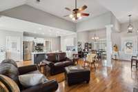 Open living room with high ceilings, dining area and kitchen with beautiful hardwood floors. Stone fireplace with gas logs, bookcase/entertainment center.