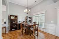 Dining room with hardwood, wainscot, crown molding, columns and chandelier
