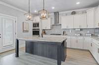 The kitchen is accented with an oversized island, granite countertops, double ovens, a gas cooktop, and walk-in pantry.