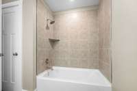 Tile surround tub/shower combo and linen closet.