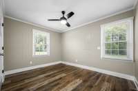 Bed 3 with ceiling fan, two windows and fresh, neutral paint.