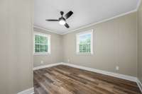 Bed 2 with two windows, ceiling fan, and fresh, neutral paint.