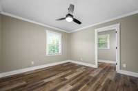 The primary bedroom with window overlooking the backyard and ceiling fan.