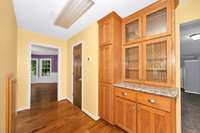 Kitchen - wood flooring, kitchen island, granite countertops, tile backsplash, stainless steel appliances, pantry