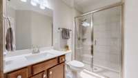 Guest bath features crown molding, tile floors, and a walk-in tile shower.  It also has a large vanity with a quartz counter and a rectangular sink.