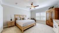 The primary bedroom features crown molding, plantation shutters, and a ceiling fan.