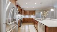 The kitchen features stainless steel appliances (the refrigerator does not convey), hardwood floors, quartz countertops, under-cabinet lighting, a tile backsplash, and a large pantry.