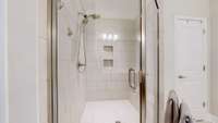 The tile shower has insets and a bench seat.