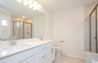 ***Photo taken from a recently completed Hampton home in the community***  The Owner's Bath includes tile flooring and dual sinks with quartz countertops.
