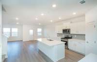 ***Photo taken from a recently completed Hampton home in the community***  The Kitchen includes white cabinetry, granite countertops and a white subway tile backsplash.