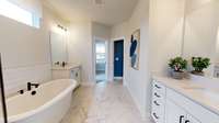 ***Photo taken from the Furman model home in Durham Farms***  The Owner's Bathroom includes tile flooring, separate sinks with quartz countertops, freestanding tub and a tiled shower with bench and rainfall shower head.