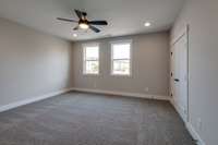 Bright and airy bedroom featuring two large windows and a ceiling fan light fixture for added comfort and style.