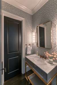 A chic powder room adorned with striking decorative wallpaper, thoughtfully designed as a stylish wet room that offers guests a memorable touch of luxury and sophistication.