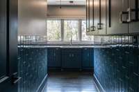 A beautifully appointed laundry room featuring eye-catching blue decorative tile, combining practicality with a fresh, stylish design that turns everyday chores into a delight. Featuring two seperate washing machine/dryer hoockups.