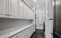 A convenient first-floor laundry room featuring plenty of counter space and cabinetry, combining everyday practicality with a clean, stylish design.
