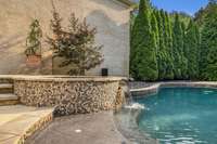 A stunning waterfall hot tub spills gracefully into the resort-style pool, creating a tranquil oasis that blends luxury and relaxation for the ultimate backyard retreat.