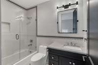 Elegant glass shower doors showcase the intricate tile craftsmanship, adding a touch of luxury and sophistication to this beautifully designed bathroom retreat.