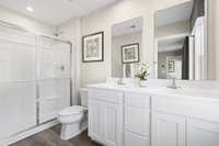 The owner's en-suite features durable luxury vinyl plank flooring, a double bowl vanity with ample storage, and a beautiful stand-up shower.