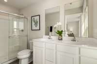 The owner's en-suite features durable luxury vinyl plank flooring, a double bowl vanity with ample storage, and a beautiful stand-up shower.