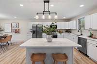 The kitchen features a wide island with a charming breakfast bar.