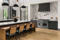 Striking quartz island with bar seating anchors the kitchen, complemented by a stainless steel stove, bold dark hood, and a stunning backsplash that ties it all together.