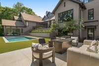 Another view of the back area—shows the door off the lower level bar area, the fire pit and the turf around the pool.