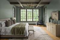 Serene primary suite on the main level featuring three oversized windows and tray ceiling—bringing in light, charm, and architectural interest. The bedroom has direct access to the outdoor living area.