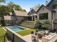 Enjoy the best of outdoor living with a sparkling pool and lush grassy area. Notice the multiple ways to access this area: from the upper terrace, from the lower level bar area, or from the exterior side of the home.