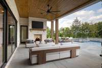 Unwind in this inviting basement-level covered living area, complete with a cozy fireplace, grilling station, all while enjoying picturesque views of the pool and spa - your perfect private retreat for year-round relaxation and entertaining.