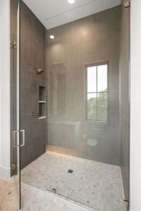 Secondary en suite showcasing a walk-in shower bathed in natural light.with an oversized floating vanity and under mont lighting.