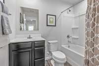 The guest bathroom has a nice vanity, durable luxury vinyl plank flooring, and a relaxing tub/shower combination.