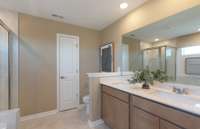 ***Photo is from a brand new Rosella home*** The owner's bathroom includes tile flooring, dual sinks with quartz countertops and a tiled walk in shower.
