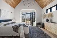 At the other end of the apartment space, a primary suite, bordered by an arched vestibule, features direct access to a private back deck.