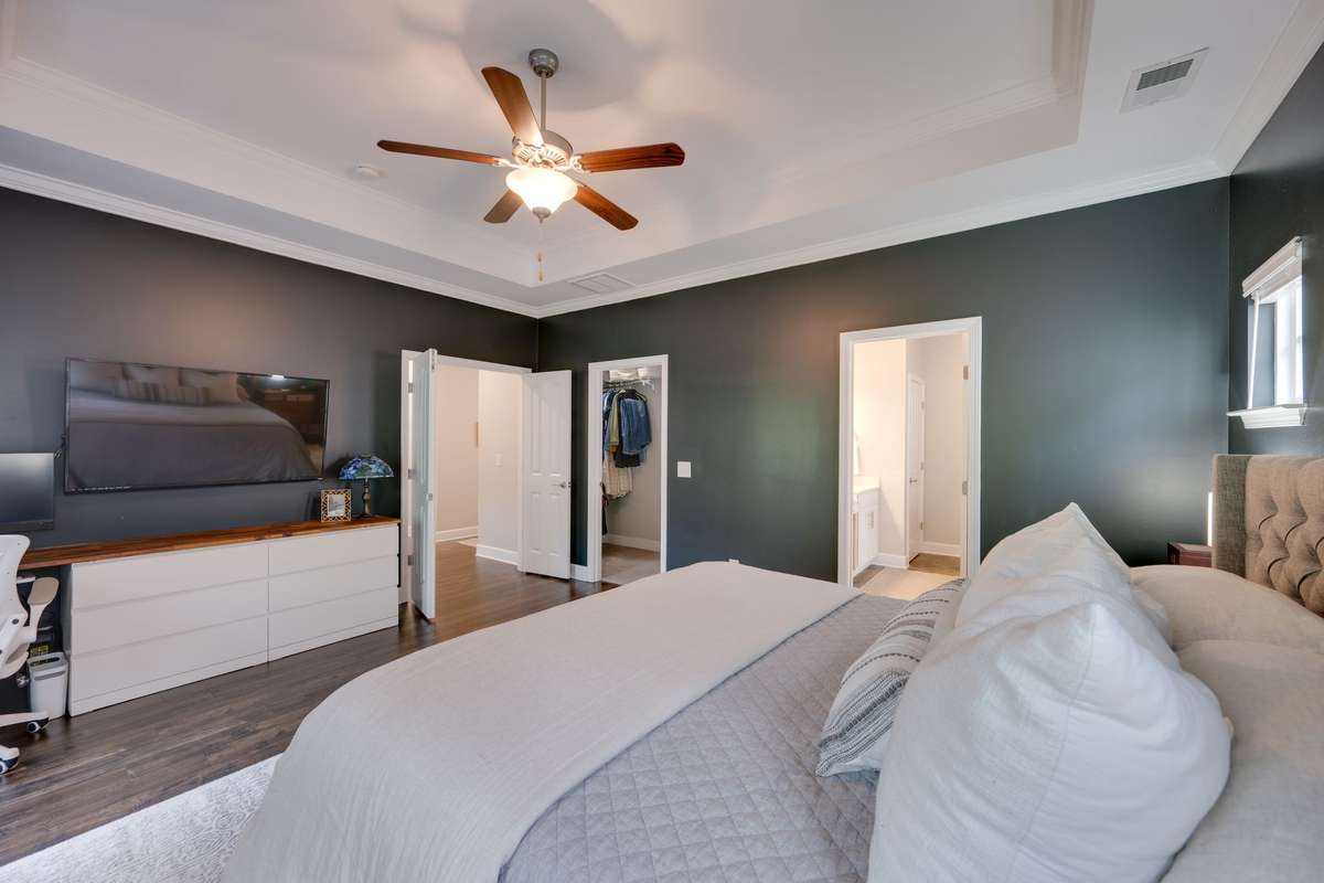 Primary bedroom with hardwood floors, ceiling fan and a trey ceiling