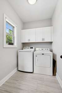 How nice to have a walk-in laundry room, especially one with overhead cabinets and a window for natural lighting!