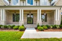 The entryway offers covered front sitting porch, modern glass entry doors, and three charming gas lanterns.