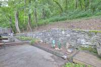 The hillside at the back of the property adds visual interest and enhances the feeling of privacy, creating a serene backdrop for outdoor living.