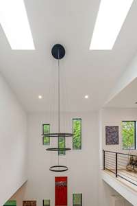 Another designer chandelier adds an artistic flair to the dining room, combining elegance with modern design on both floor levels