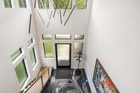 The curated architectural design starts with a solid steel floating staircase, an artistic foyer floor illuminated by accent lighting, and a captivating chandelier