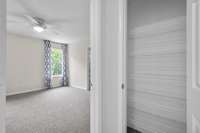 Second upstairs suite with new Berber carpet, ceiling fan, and a peaceful view of the tree line. Just outside the room, a deep hallway linen closet offers plenty of shelving for towels, bedding, or overflow storage.